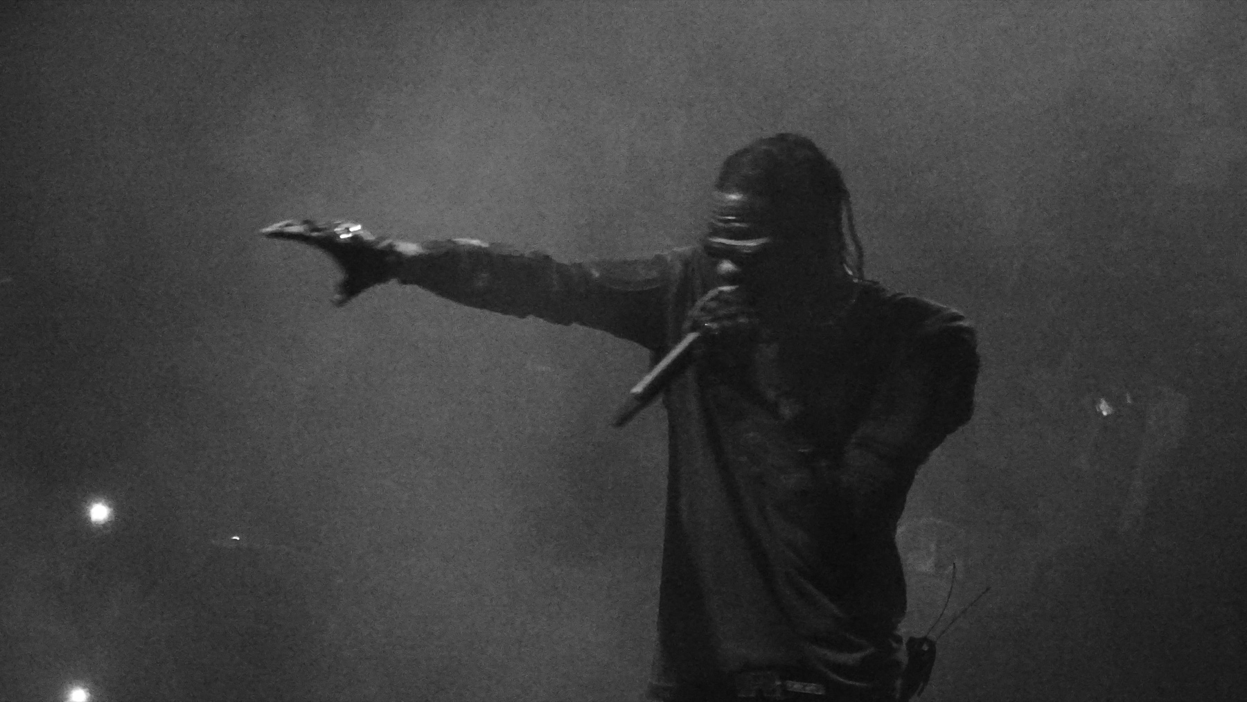 Travis Scott performing live, backlit through stage haze