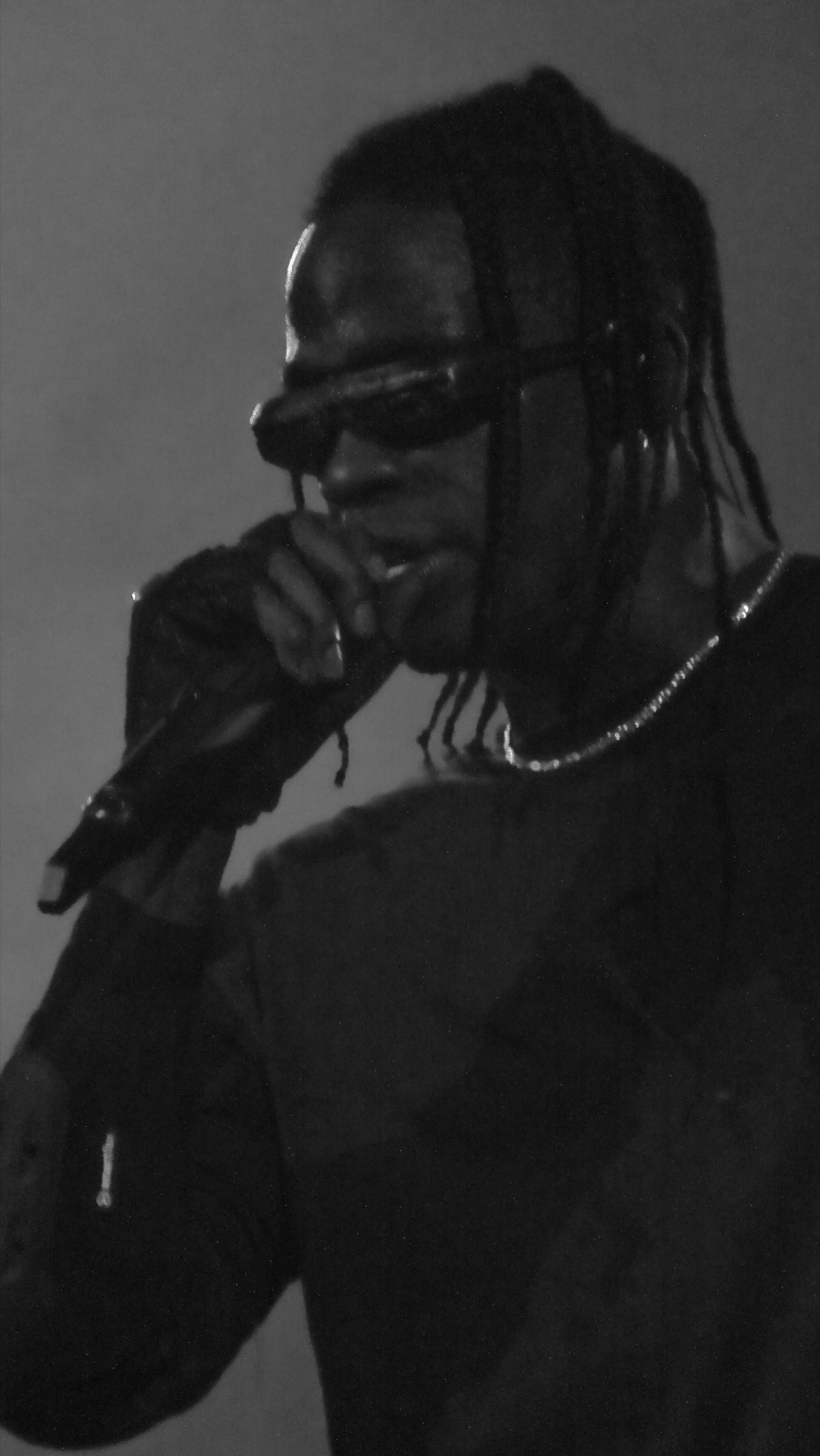 Travis Scott performing live, backlit through stage haze