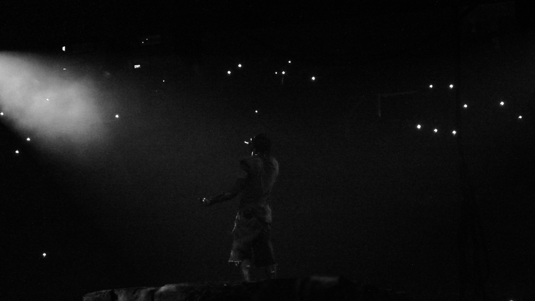 Travis Scott performing live, backlit through stage haze