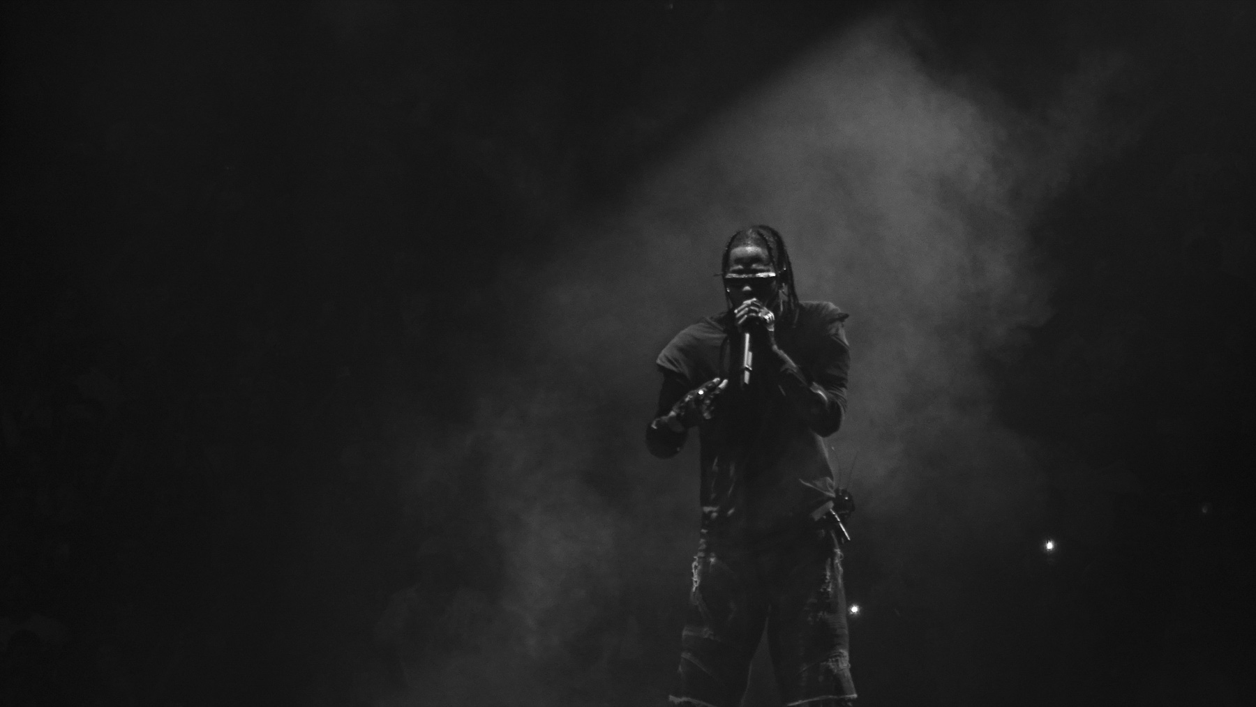 Travis Scott performing live, backlit through stage haze