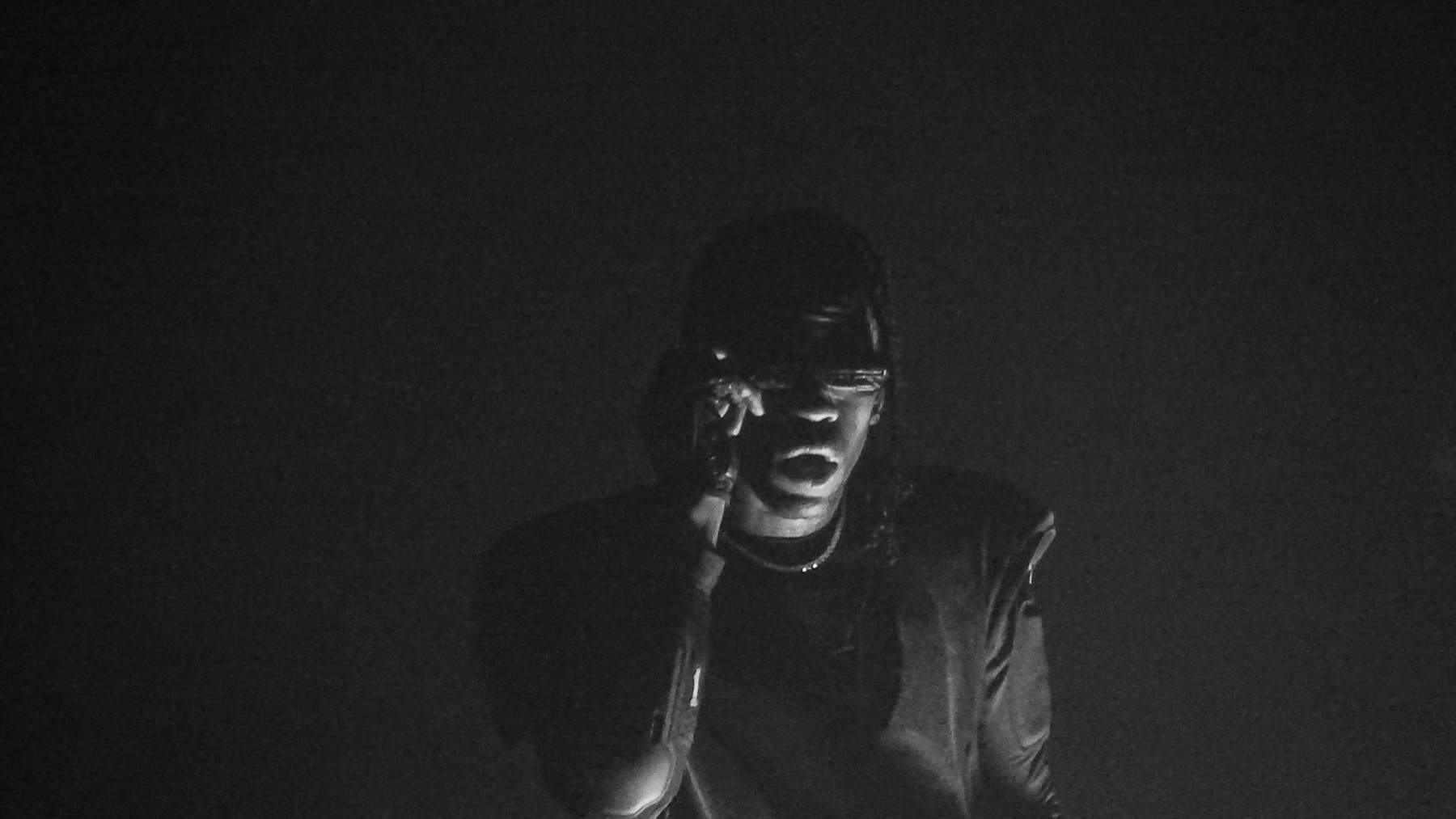 Travis Scott performing live, backlit through stage haze