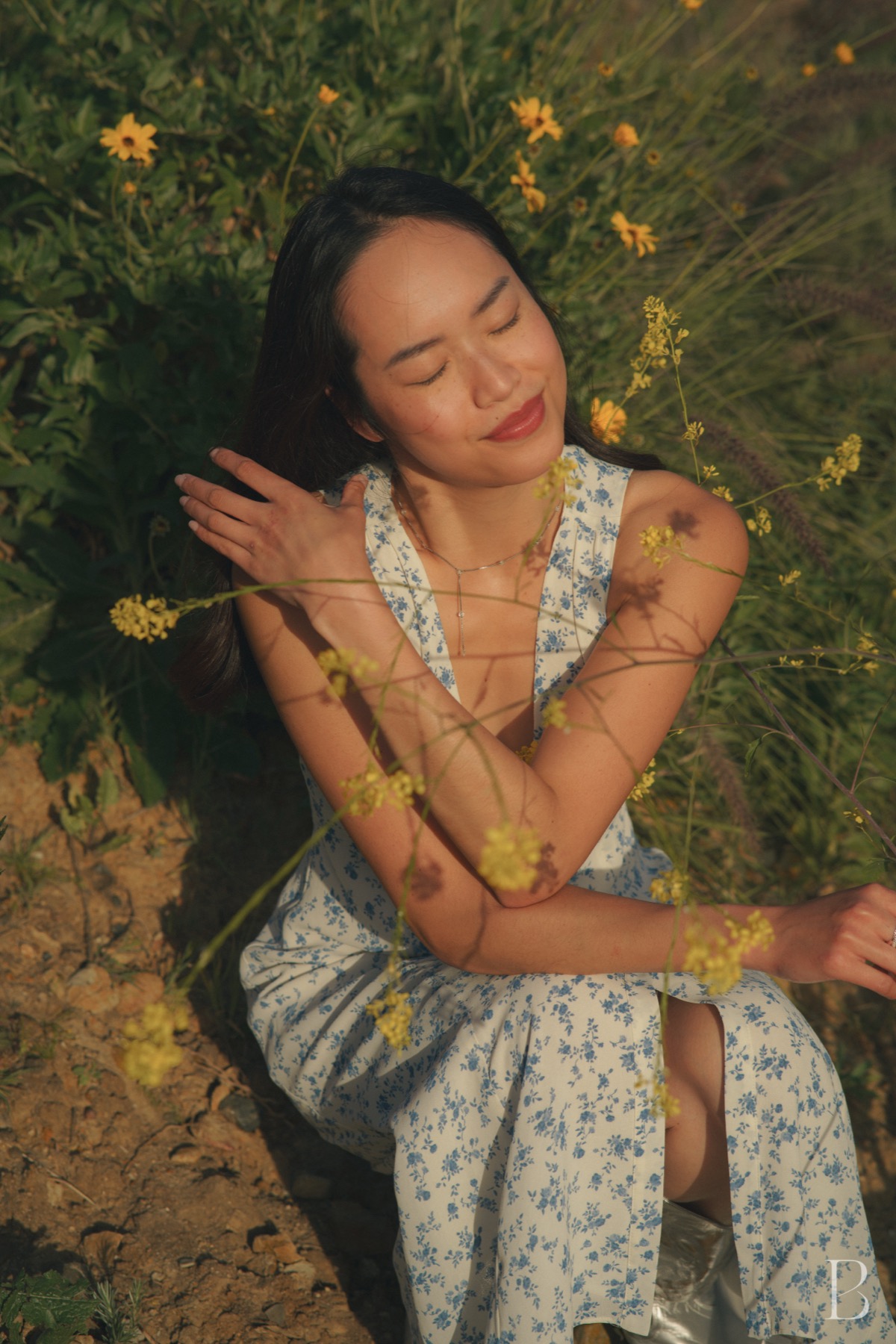 Model lying among yellow wildflowers in a printed dress