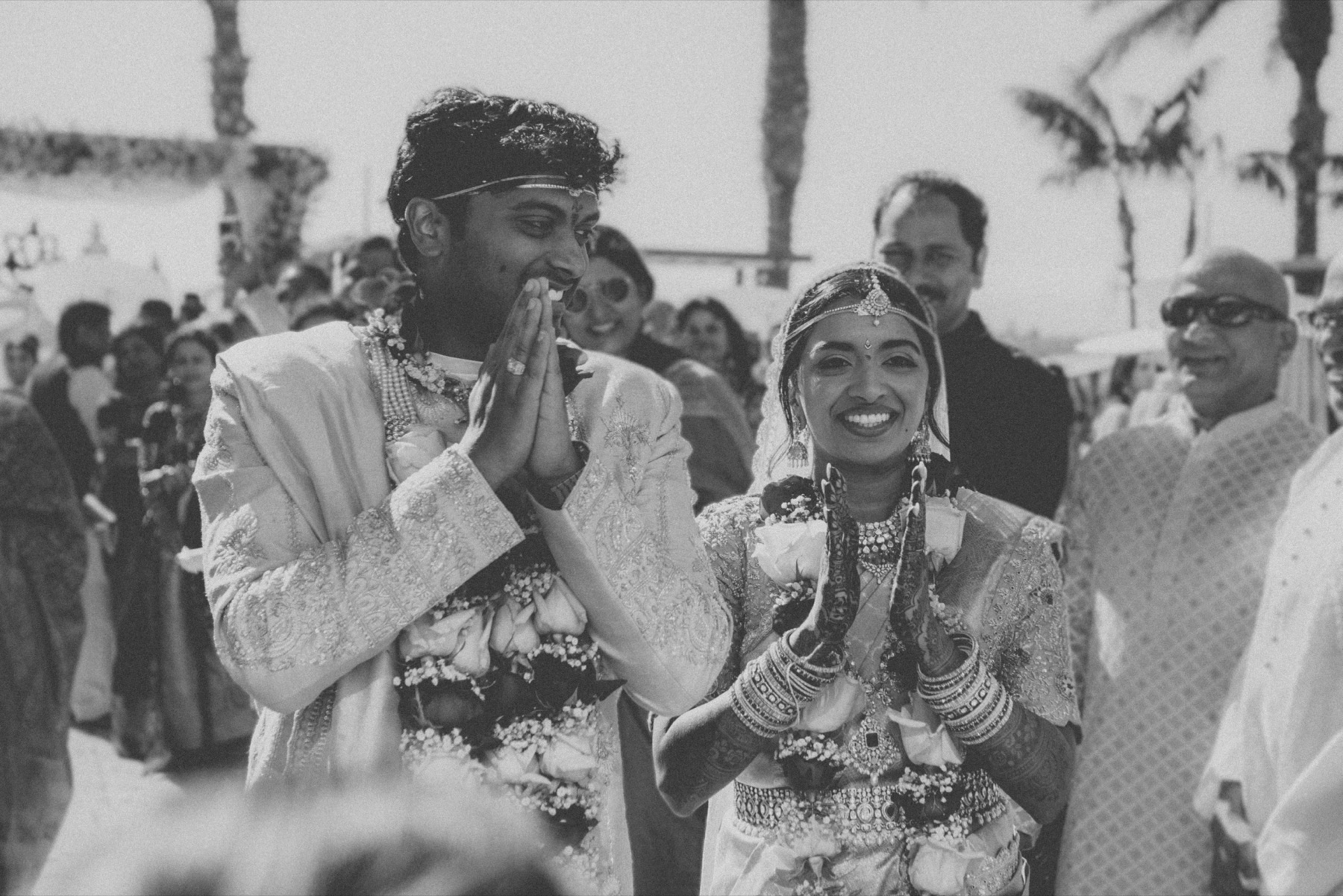 The couple greeting their guests with folded hands, black and white